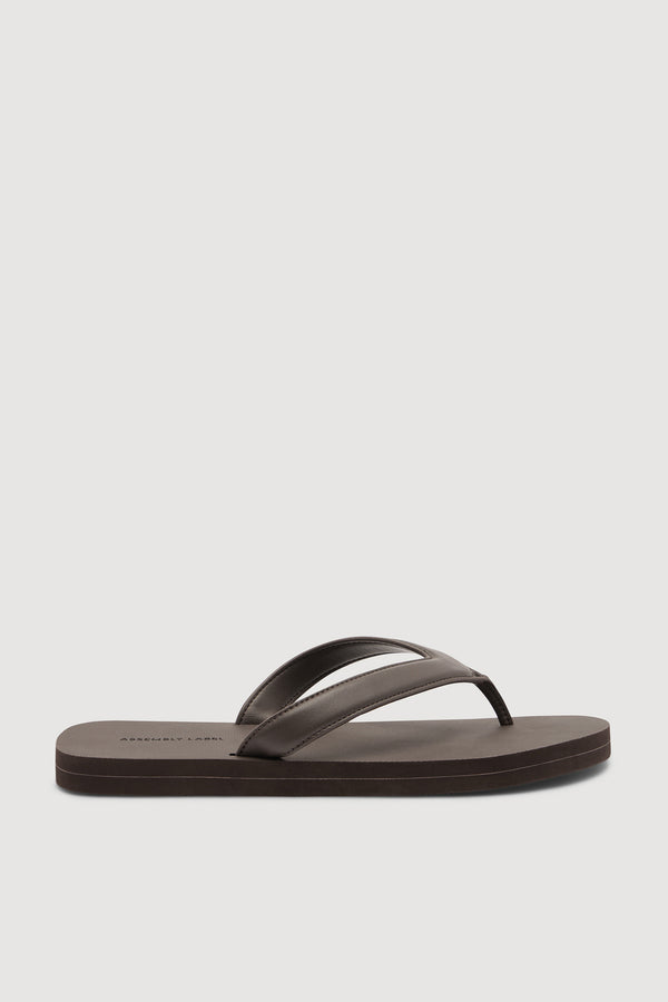 A single dark brown leather flip-flop sandal shown from a side profile view against a white background.