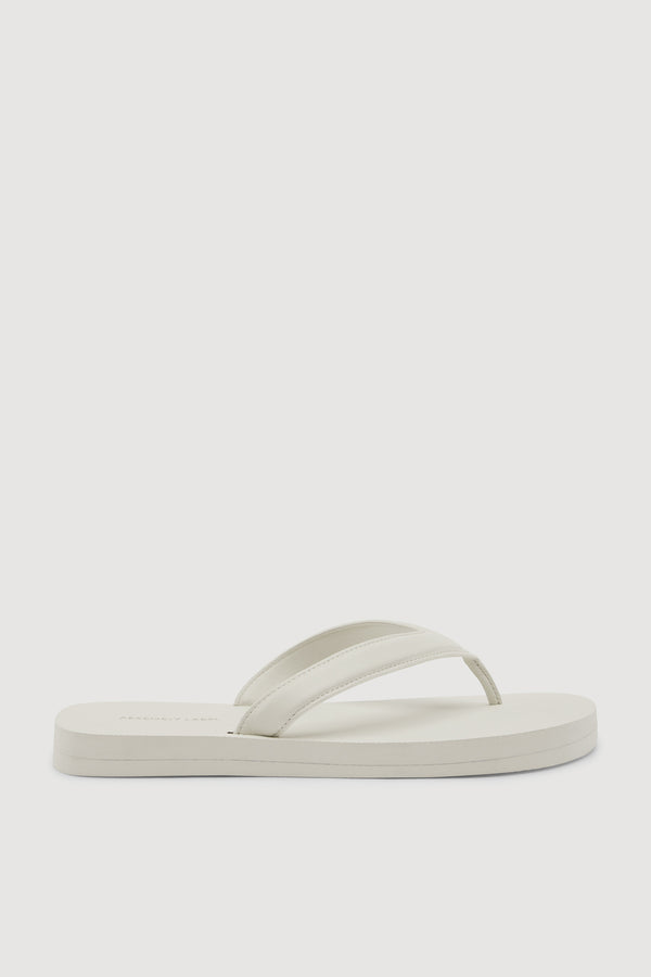 A single off-white leather flip-flop sandal shown from a side profile view against a white background.