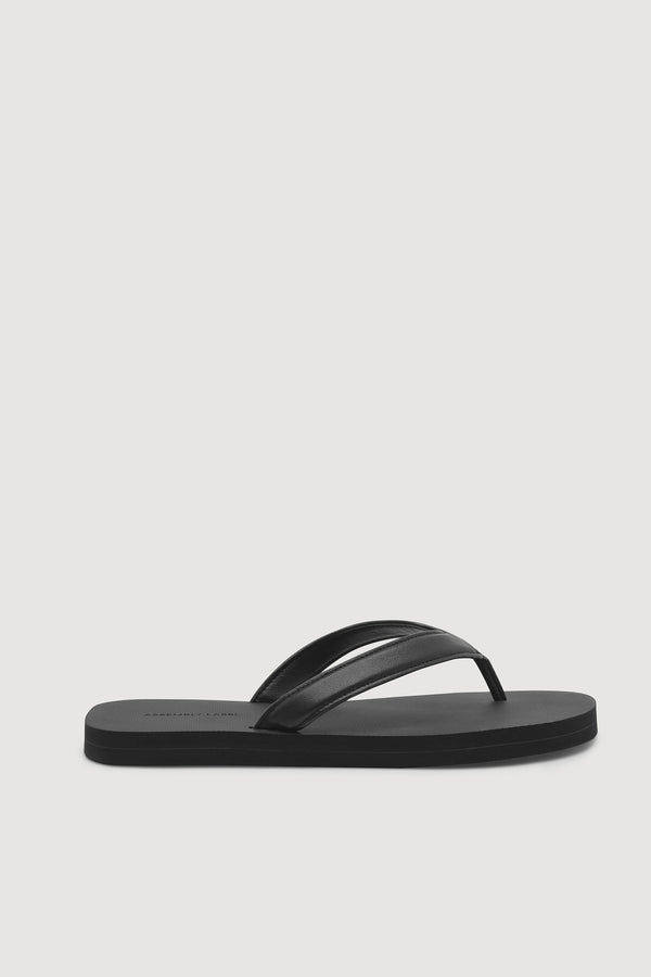 Black flip flop sandal with a rubber sole, leather straps on a white background.
